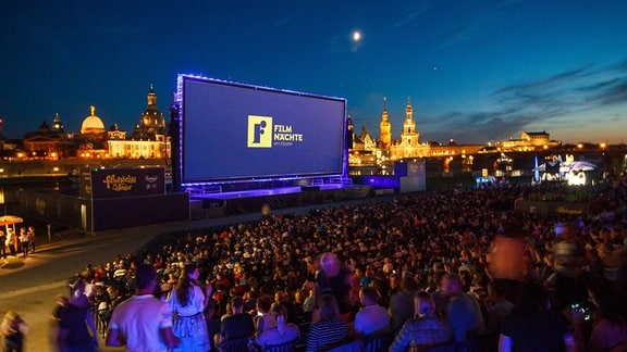 Zahlreiche Gäste der "Filmnächte am Elbufer" schauen auf eine Kinoleinwand. Im Hintergrund ist die Kulisse der Dresdner Altstadt mit der Kuppel der Kunstakedemie (l-r), der Frauenkirche, dem Hausmannsturm, der Hofkirche und der Semperoper zu sehen.