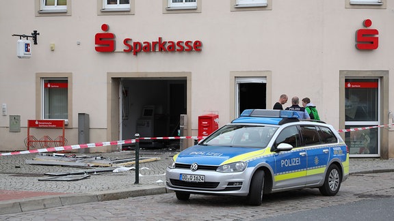 Ein Streifenwagen steht vor dem beschädigten Sparkassengebäude in Wilsdruff.