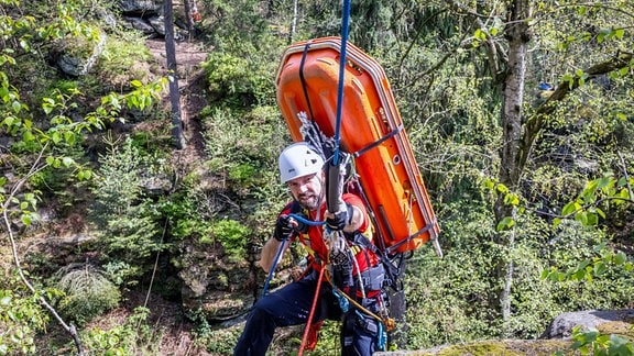 Eine Rettungskraft der Bergwacht hält sich an einem Seil fest.
