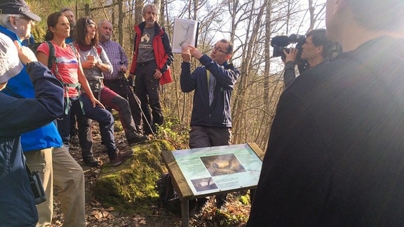 Eine Mann zeigt einer Gruppe ein Bild im Wald