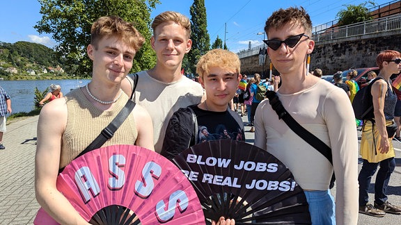 Eine Gruppe von jungen Männern hält Fächer und lächelt in die Kamera.  