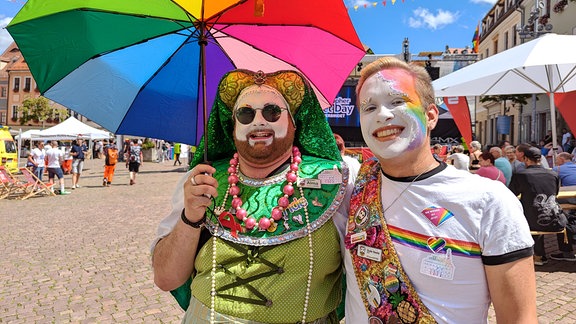 Zwei bunt kostümierte Männer auf dem CSD Pirna lächeln in die Kamera.  