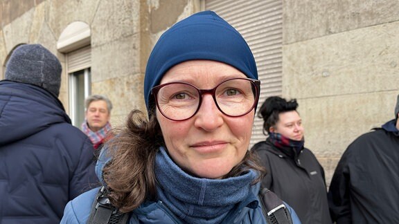 Eine Frau mit Brille und blauer Kleidung schaut in die Kamera. 