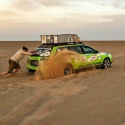 Οι άνθρωποι τραβούν και σπρώχνουν αγωνιστικά αυτοκίνητα από την άμμο