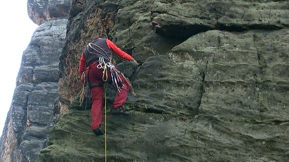 Ein Mann klettert an einem Felsen. 