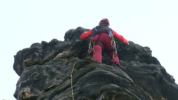 Ein Mann klettert an einem Felsen. 