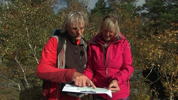 Ein Mann und eine Frau schauen zusammen auf ein Notizblatt. 