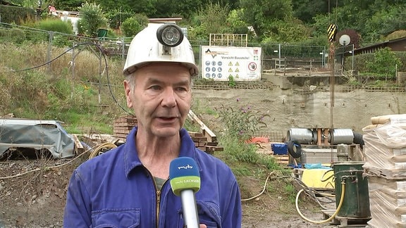 Ein Mann mit Helm vor einer Baustelle