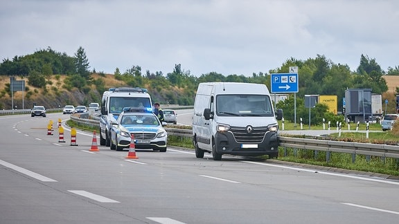 Ein Transporter steht mit der Fahrerseite an der Leitplanke der Autobahn, dahinter zwei Polizeifahrzeuge.