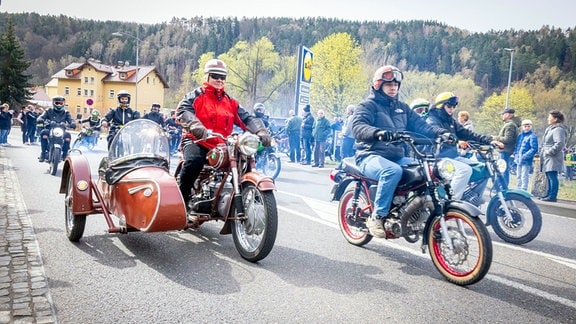 Ein Jawa-Motorrad mit Beiwagen fährt zusammen mit Simson-Mopeds durch Bad Schandau. 