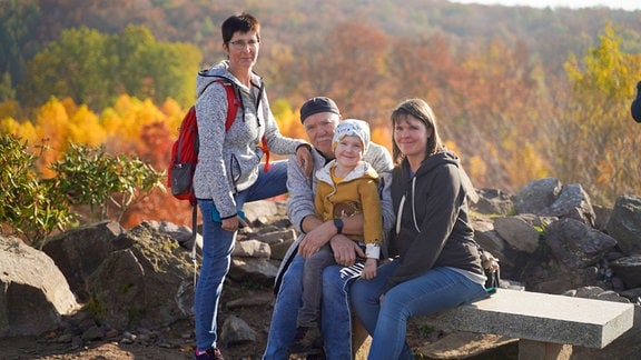 Eine Familie sitzt auf einer Bank in der Natur