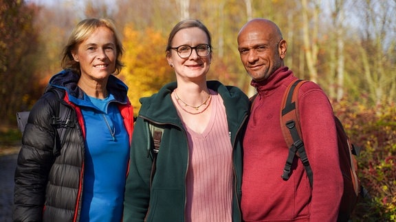 Drei Personen stehen in der Natur