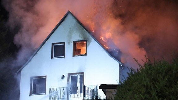 Flammen schlagen aus einem Wohnhaus, es herrscht Dunkelheit