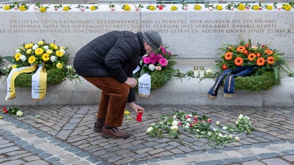 Ein Mann stellt auf dem Altmarkt an einer Gedenkstätte für die Opfer der Bombardierung Dresdens im Zweiten Weltkrieg vor 75 Jahren ein Grablicht auf
