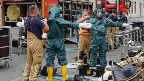 Feuerwehrleute ziehen Schutzanzüge an für den Gefahreneinsatz auf dem Werksgelände der Nudelfabrik Riesa-