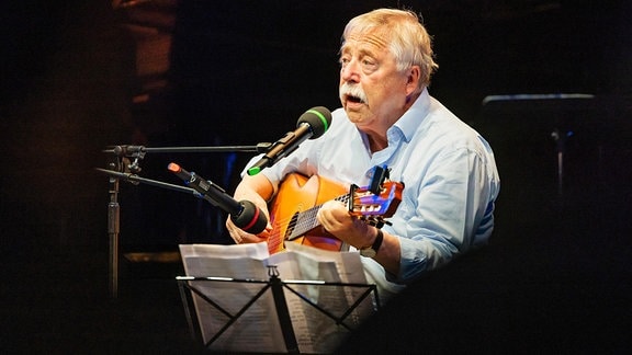 Wolf Biermann, ein Mann spielt Gitarre und singt in ein Mikrofon