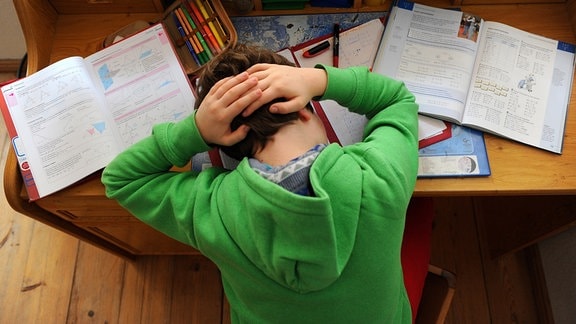 Ein Schüler hält sich während der Arbeit an den Hausaufgaben seinen Kopf. 