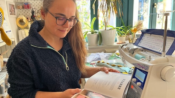 Eine Frau sitzt in einem Zimmer und liest ein Buch. 