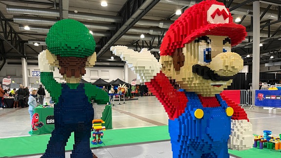 Zwei lebensgroße Super-Mario-Figuren stehen auf einem Tisch. 