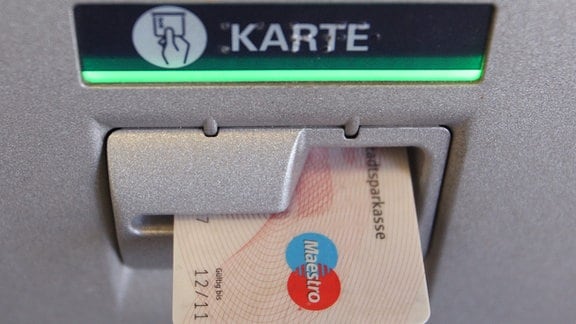 Eine EC-Karte steckt im Eingabeschlitz eines Geldautomaten. 