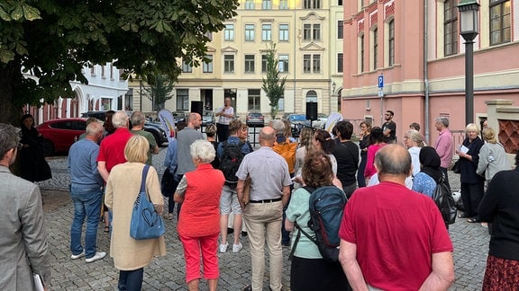 Zahlreiche Menschen haben sich auf einem Platz in einer Altstadt versammelt.