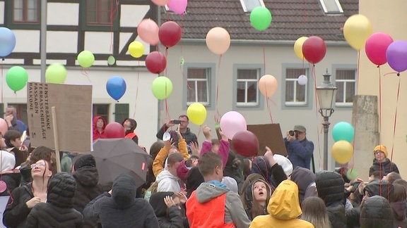 Schüler lassen bunte Ballons in den Himmel steigen.