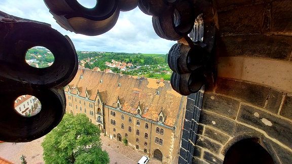 Von einem Turm aus blickt man auf ein großes alten Gebäude, dass auf einem Plateau steht. Es ist der Blick vom Dom Mei0ßen auf das ungenutzte Baudenkmal namens Kornhaus auf dem Meißner burgberg. 