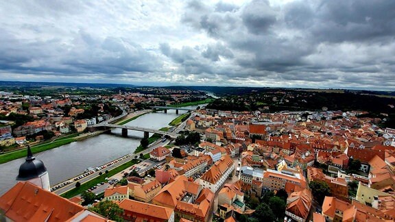 Blick über Dächer einer Altstadt, daneben ein Fluß und weite, grüne Hänge. Es ist der Blick aus 62 Metern Höhe über die Stadt Meißen Richtung Dresden und Sächsische Schweiz.