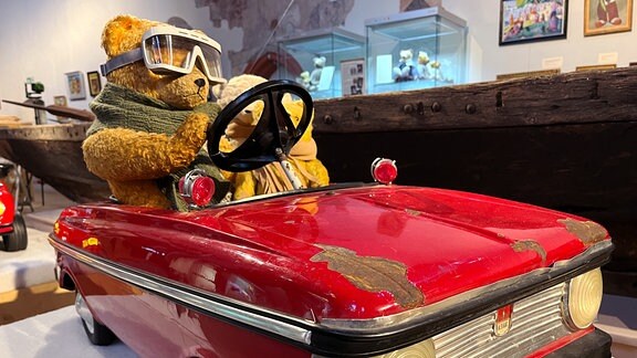 Ein Teddy sitzt in einem roten Sportwagen
