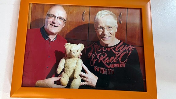 Ein Bilderrahmen mit einem Bild von zwei Männern, die einen Teddy halten