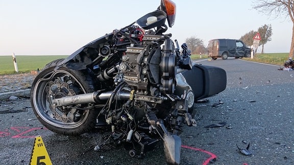 Auf einer Straße liegt ein zerstörtes Motorrad