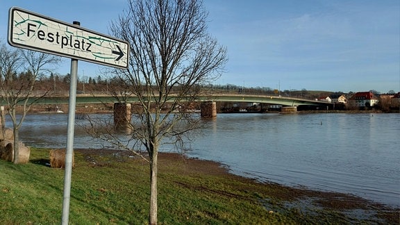 Auf einer Wiese steht ein Schild, das den Schriftzug "Festplatz" trägt. Von dem Platz an sich ist nichts zu sehen, denn Elbehochwasser hat alles überspült. Der Wasserstand war am 27.12.2023 zu sehen, danach stig das Wasser noch um einige Zentimeter an.