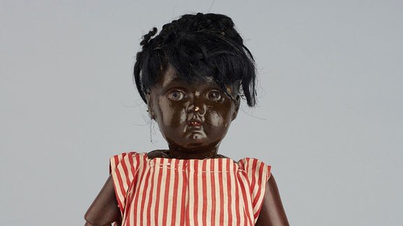 Die Puppe eines schwarzen Mädchens mit gestreiftem Kleid.