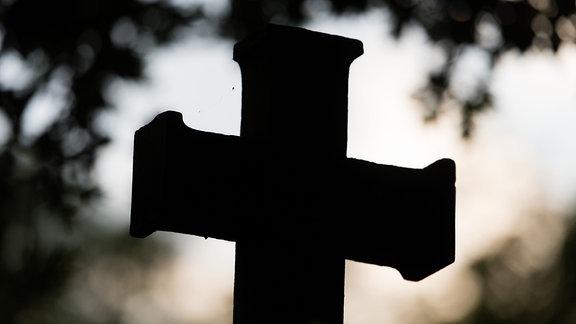 Ein Kreuz steht auf einem Friedhof.