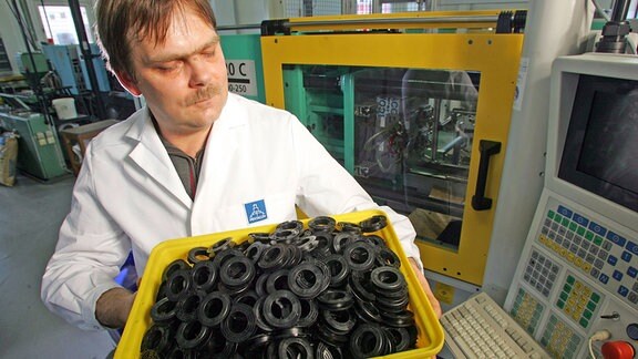 Kunststoffverarbeiter Sven Sorge zeigt Spulenkörper der Firma Pentacon GmbH in Dresden