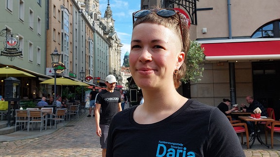 Eine junge Frau mit kurzen Haaren schaut lächelnd in die Kamera.