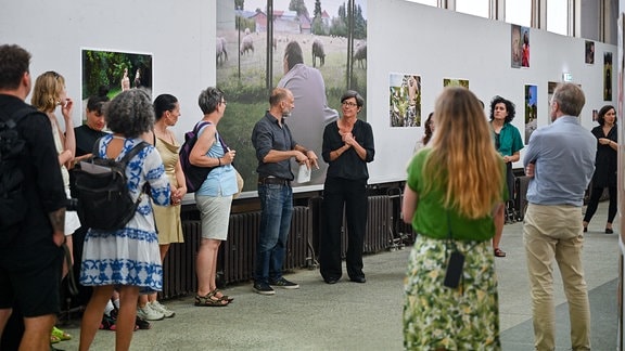 Menschen unterhalten sich in einer Ausstellung, in der Mitte Christiane Mennicke-Schwarz (Leiterin Kunsthaus Dresden)