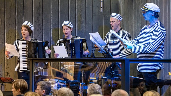 Auf einer Bühne singen und spielen zwei Musikerinnen und zwei Musiker in Matrosenkleidung