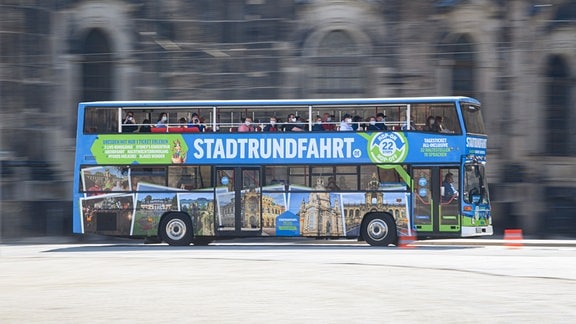 Ein blauer Doppeldecker-Bus fährt mit Touristen über den Theaterplatz in Dresden