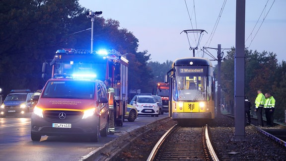 Eine Straßenbahn ist abseits eine Haltestelle zum Stehen gekommen, daneben steht ein Feuerwehrfahrzeug
