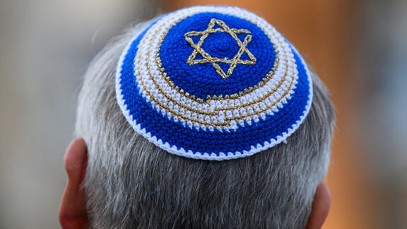Ein Mann trägt eine Kippa mit Judenstern. 