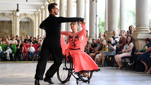 Ein Paar tanzt, die Frau sitzt im Rollstuhl