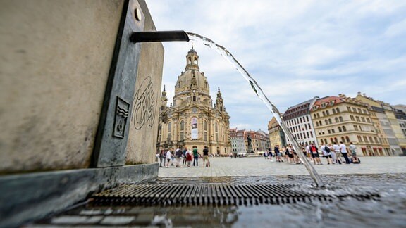 Wasser läuft aus einem Trinkwasserbrunnen auf dem Neumarkt in der Altstadt von Dresden vor der Frauenkirche.