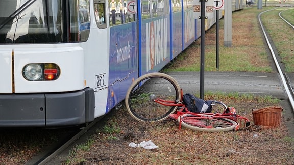 Ein Fahrrad liegt neben einer Straßenbahn auf einer Grünfläche an den Gleisen. 