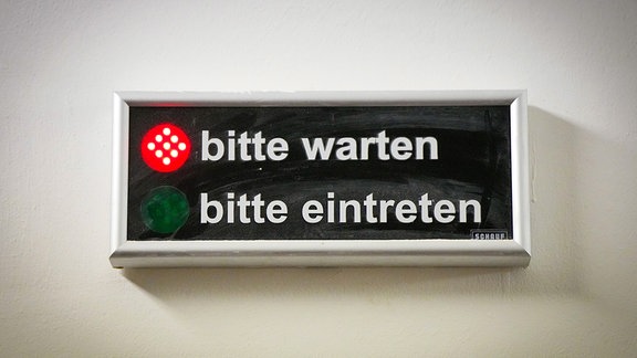 Ein Display mit der Aufschrift "bitte warten" und "bitte eintreten" hängt neben einer Tür zu einem Amtszimmer im Gerichtsgebäude in Moabit. 