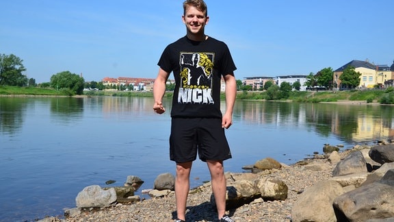 Ein junger Mann steht an einem Flussufer