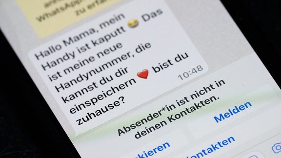 Auf dem Display eines Smartphones steht eine Whats App-Nachricht, die im Tonfall betrügerischen Nachrichten nachempfunden ist, die dazu genutzt werden, Geld zu bekommen.