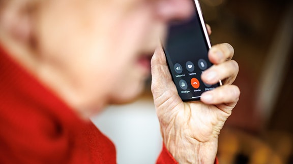 Eine über 90-jährige Dame führt mit ihrem Smartphone ein Telefongespräch.