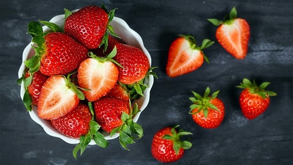 Draufsicht auf Erdbeeren in einer Schale mit frischen reifen ganzen und halbierten Erdbeerfrüchten