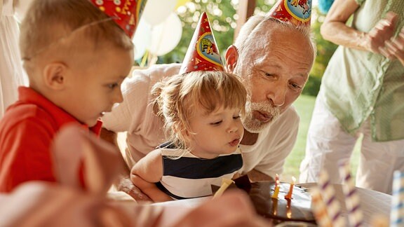 Ein Mann und zwei Kleinkinder an einem Geburtstagstisch
